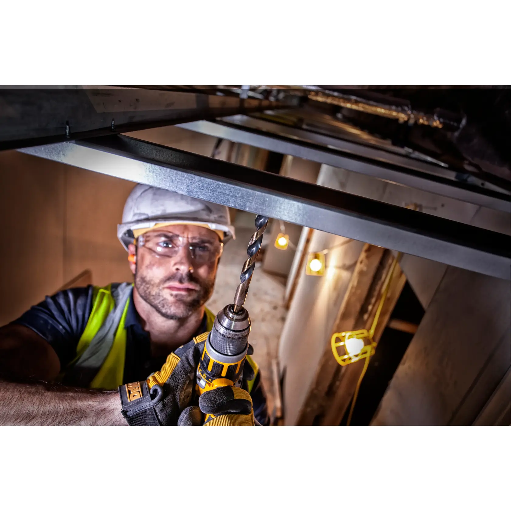 Worker uses DEWALT drill with DT70755 bit for metal frame installation at a construction site.