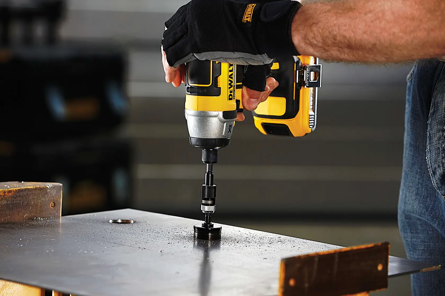Photo of DEWALT DT71514 impact driver in use drilling metal sheet, user wearing gloves, close-up side view.