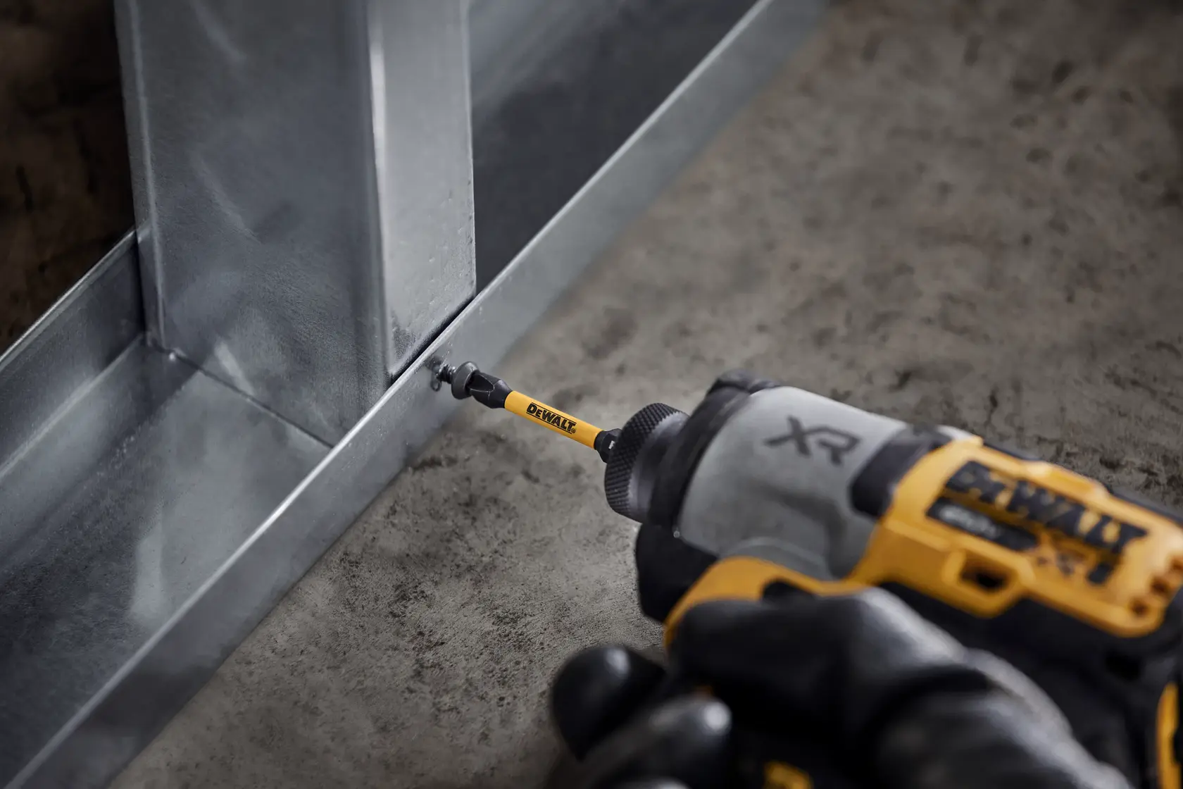 Photo of DEWALT bit in use with electric drill driving screw, SKUs DT7275, DT7275-QZ, on metal frame.