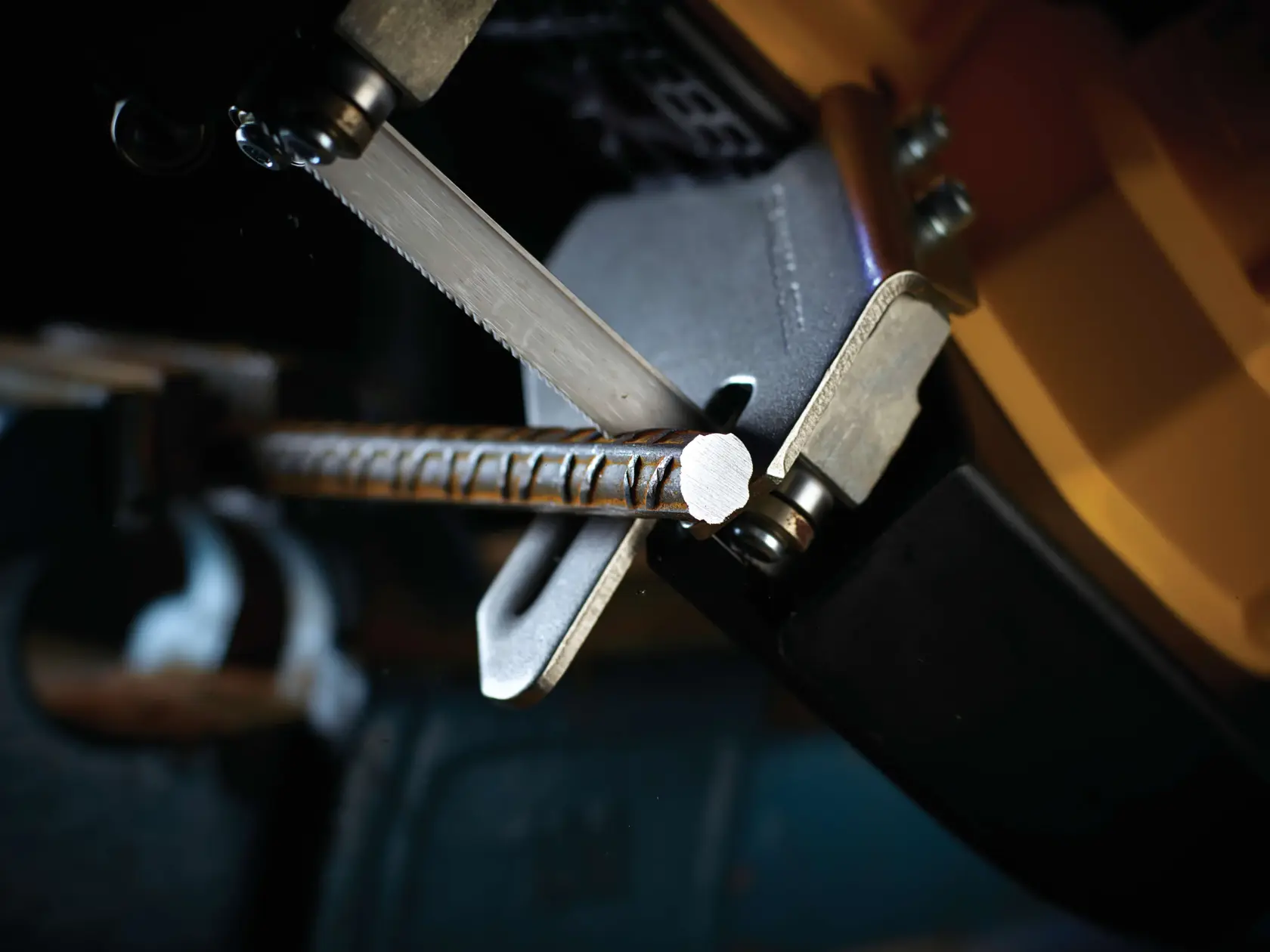 Close-up of a DEWALT saw cutting through a metal rebar in a workshop setting.