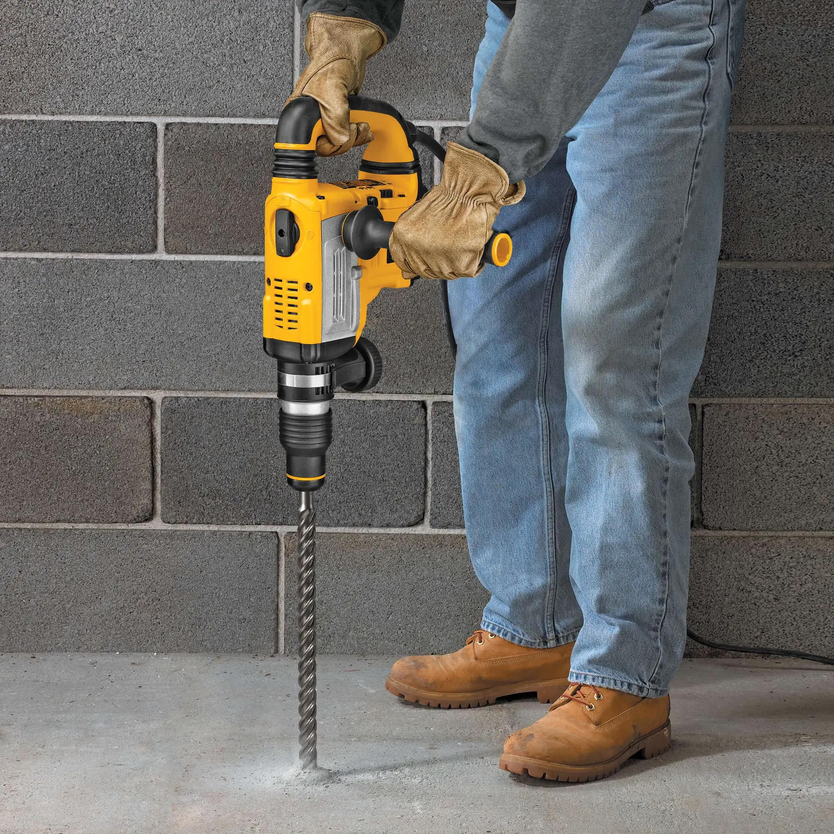 Photo of DEWALT DT9448 rotary hammer drill in use on concrete floor, yellow and black, construction scene.