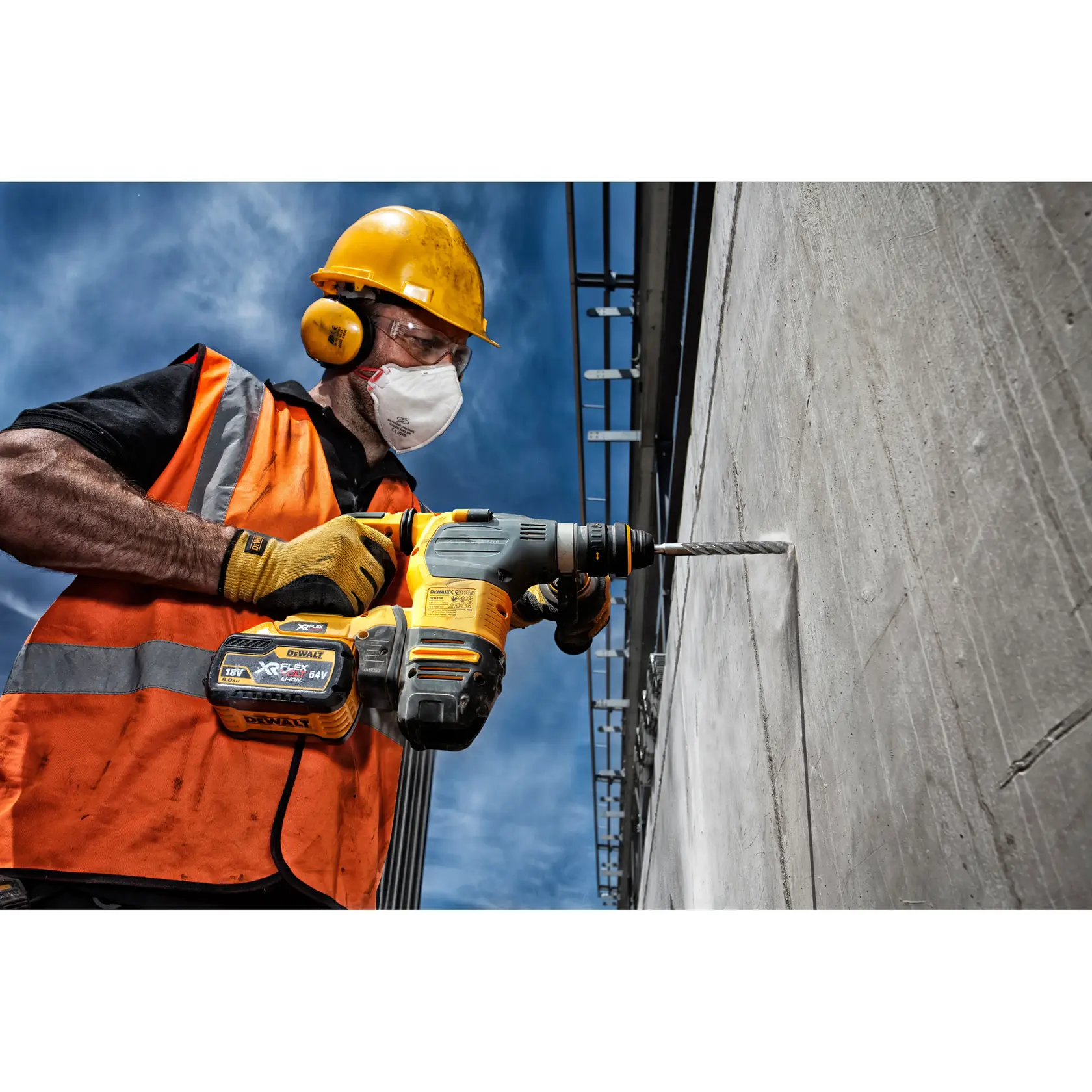 Trabajador perfora pared de hormigón con DEWALT DT9568, al aire libre con casco y chaleco.