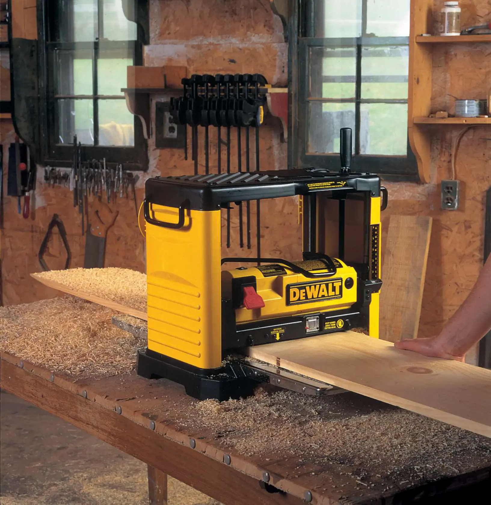 Cepillo DEWALT DW733 sobre mesa de trabajo, en taller, trabajando una tabla de madera.