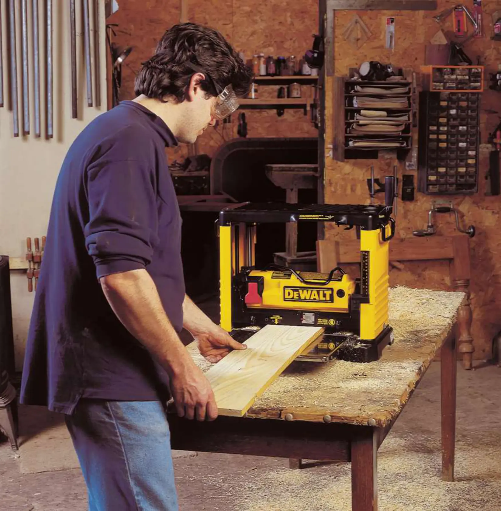 Persona usando una cepilladora amarilla DEWALT DW733 en un banco de taller.