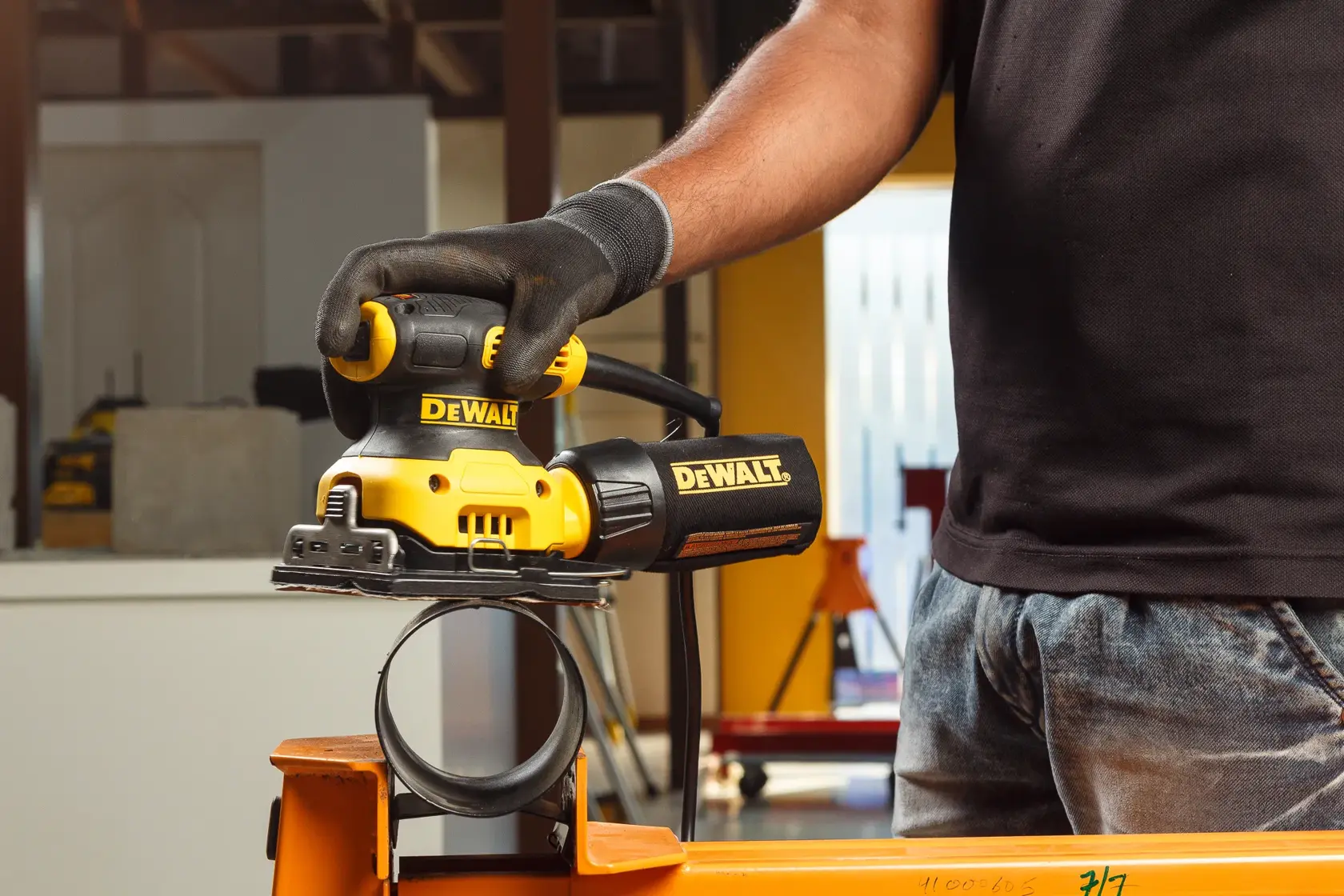 Manos conectan una manguera a una herramienta DEWALT amarilla, usada para trabajar o lijar madera.