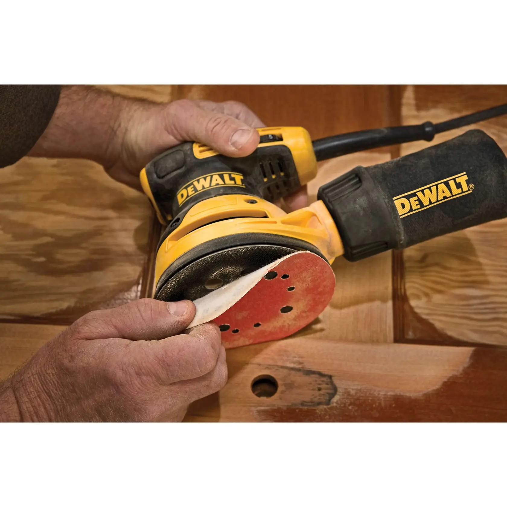Eine elektrische DEWALT Exzenterschleifer, Modell DWE6423, in Schwarz und Gelb gezeigt, mit angeschlossenem Netzkabel. Der Schleifer hat ein sichtbares Geschwindigkeitsregelrad und ist für glatte Schleifoberflächen konzipiert.