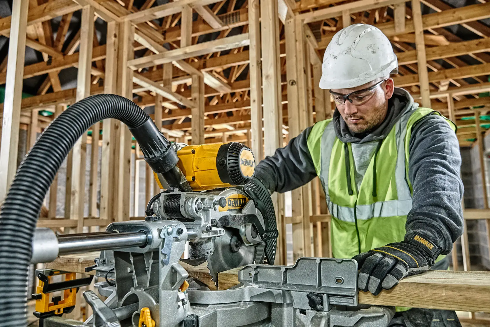Arbeiter nutzt DEWALT DWS727 Säge auf Baustelle, trägt Schutzausrüstung und Handschuhe.