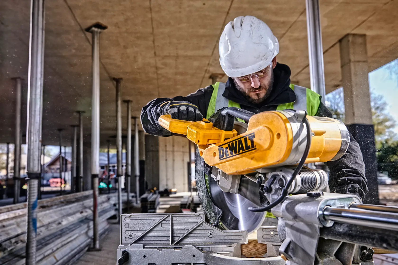 DEWALT DWS780, DWS780KIT saw in use at a construction site. Worker wears safety gear. Photography product category.