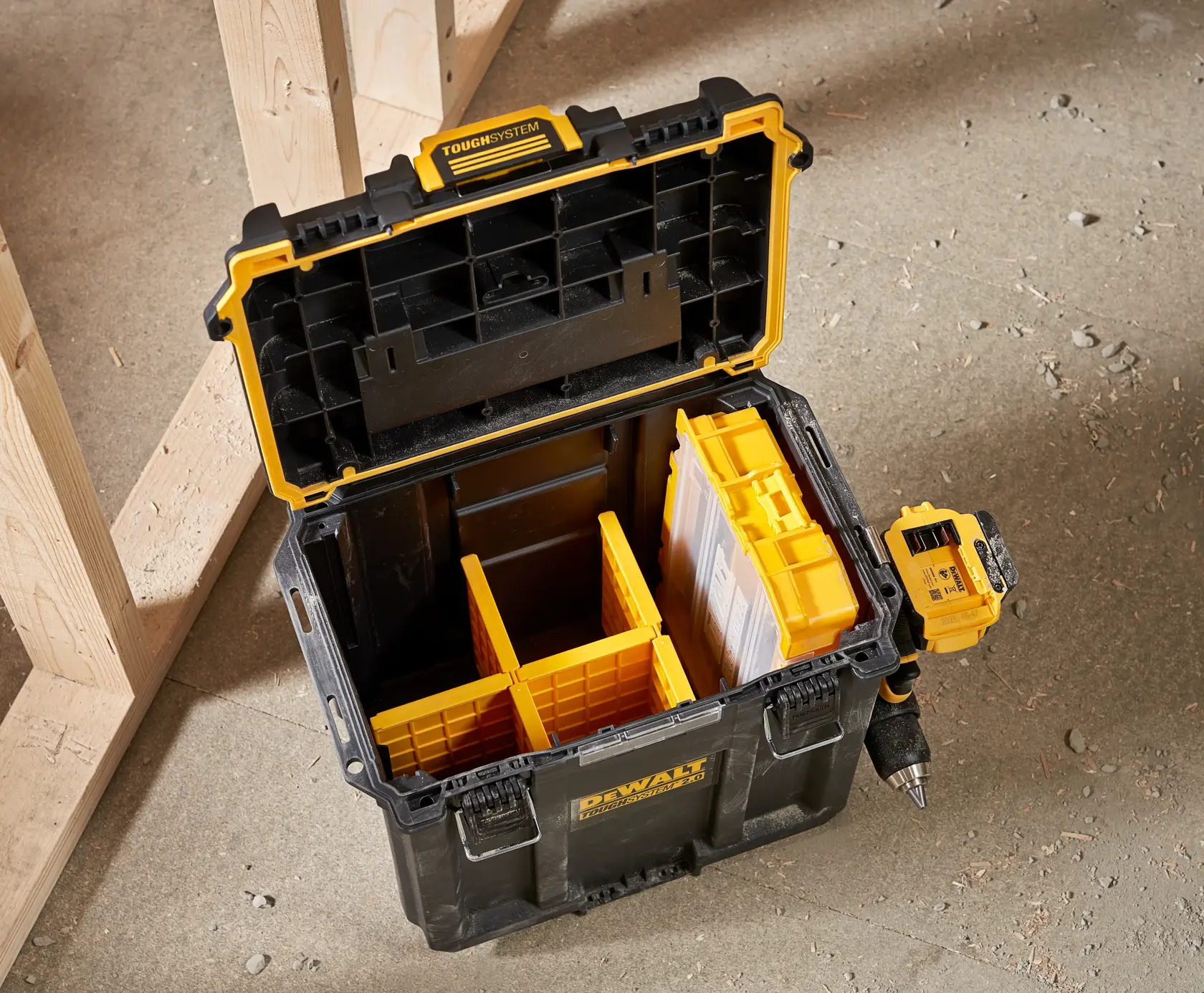 Photo of DEWALT DWST08035-1 black and yellow tool box with open lid, yellow dividers, and drill on concrete.