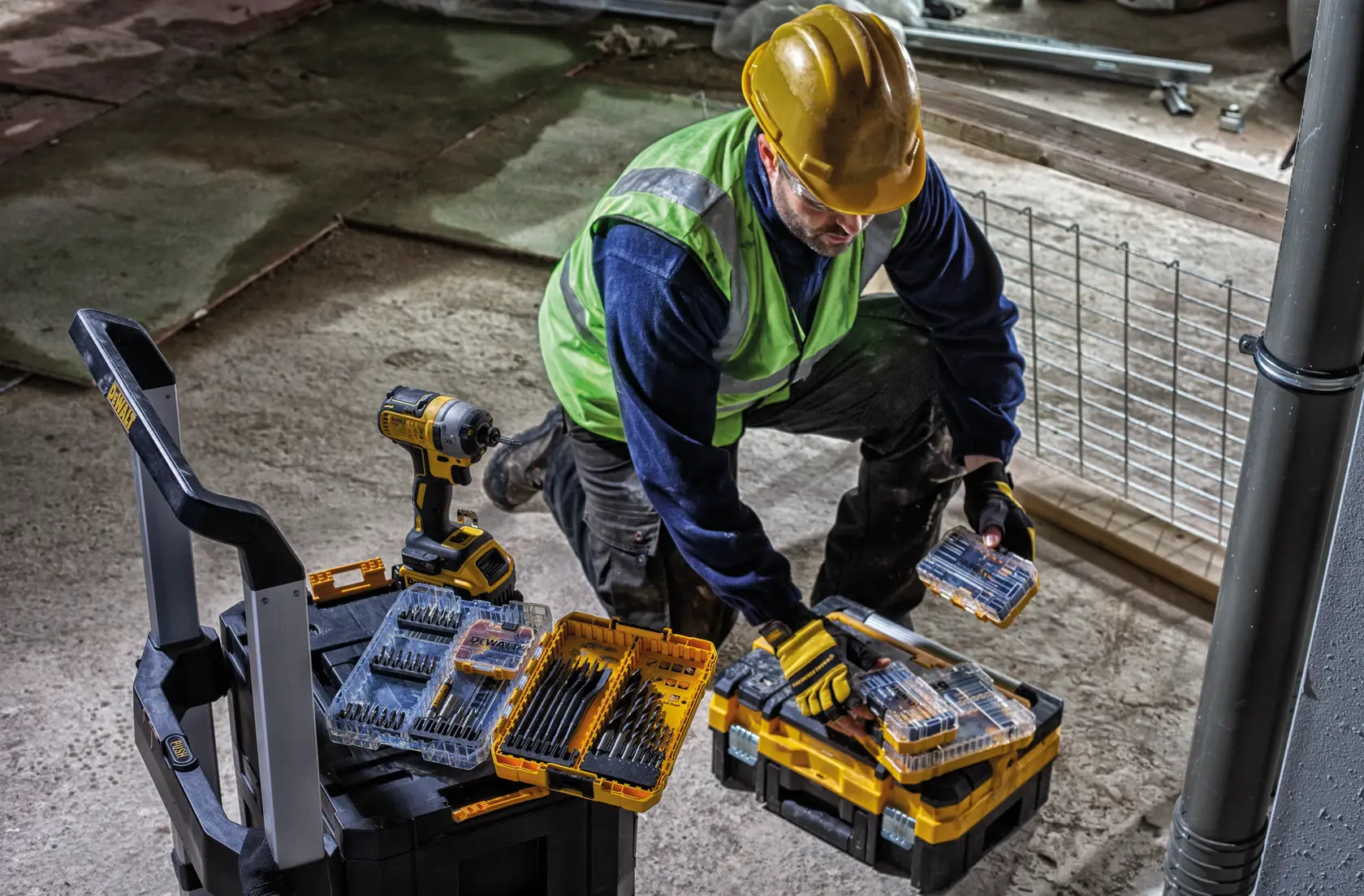 A DEWALT rolling carrier trolley with a sturdy frame, two large rear wheels, and one smaller front wheel. The trolley has a handlebar and features locking mechanisms for securing loads, suitable for transporting equipment, tools, or cases.
